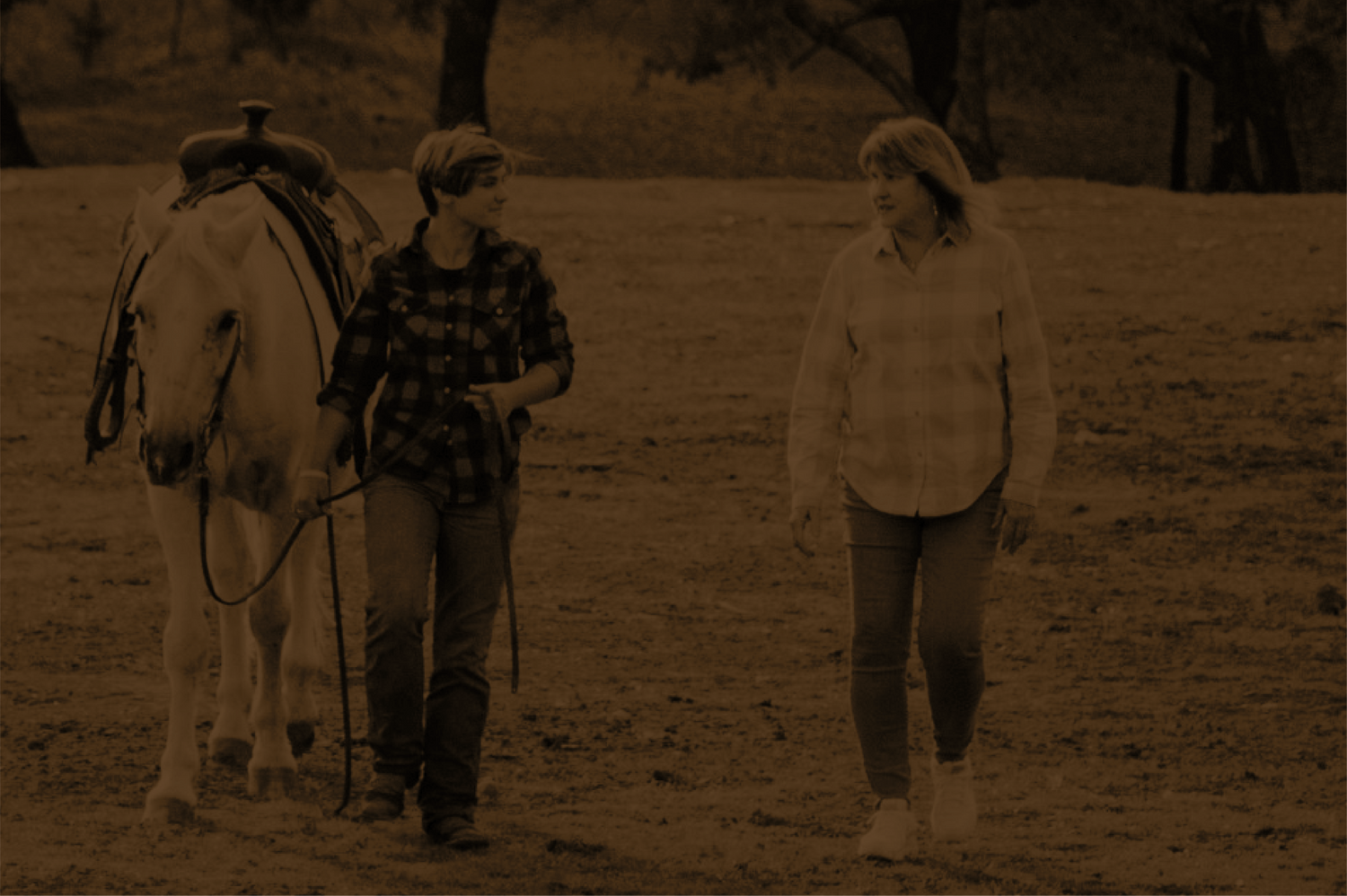 A young woman in her late teens and a professional adolescent counselor walking and talking during a therapeutic horsemanship session at Rustic Way Ranch, an equine-assisted psychotherapy center for teens struggling with mental health.