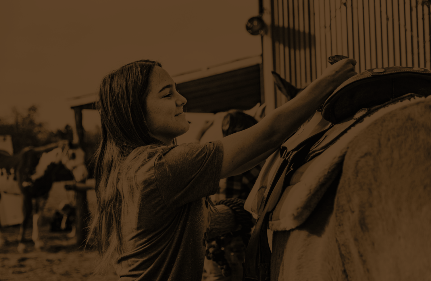 A young woman in her late teens saddling a horse before her therapeutic horsemanship session at Rustic Way Ranch, an equine-assisted psychotherapy center for teens struggling with mental health.