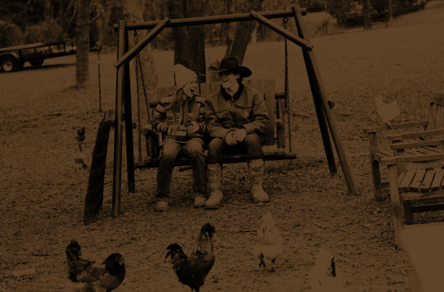 A teen boy and teen girl sitting on a wooden bench swing during a nature-based experiences session at Rustic Way Ranch, an equine-assisted psychotherapy center for teens struggling with mental health.